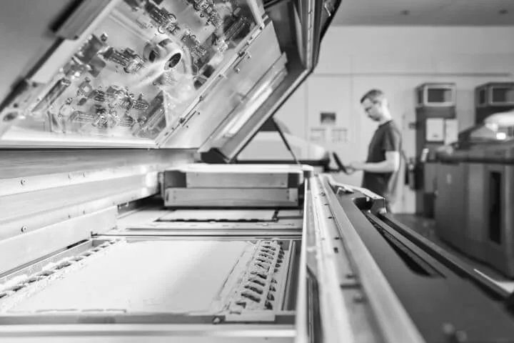 Multi Jet Fusion Drucker bei 3Faktur mit einem Mitarbeiter im Hintergrund vor einer geöffneten Maschine